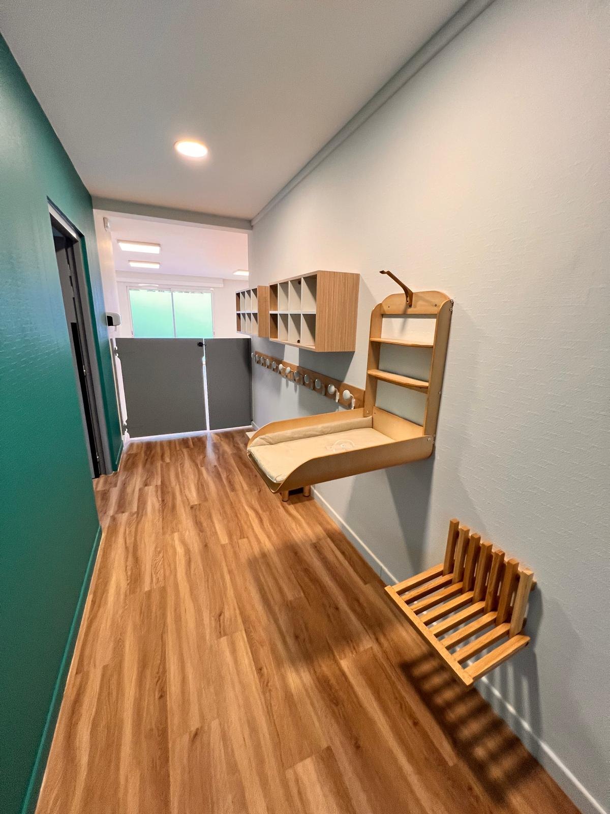 Espace de change de la micro-crèche Mélisse à Dachstein avec table à langer murale en bois et escalier d’accès escamotable
