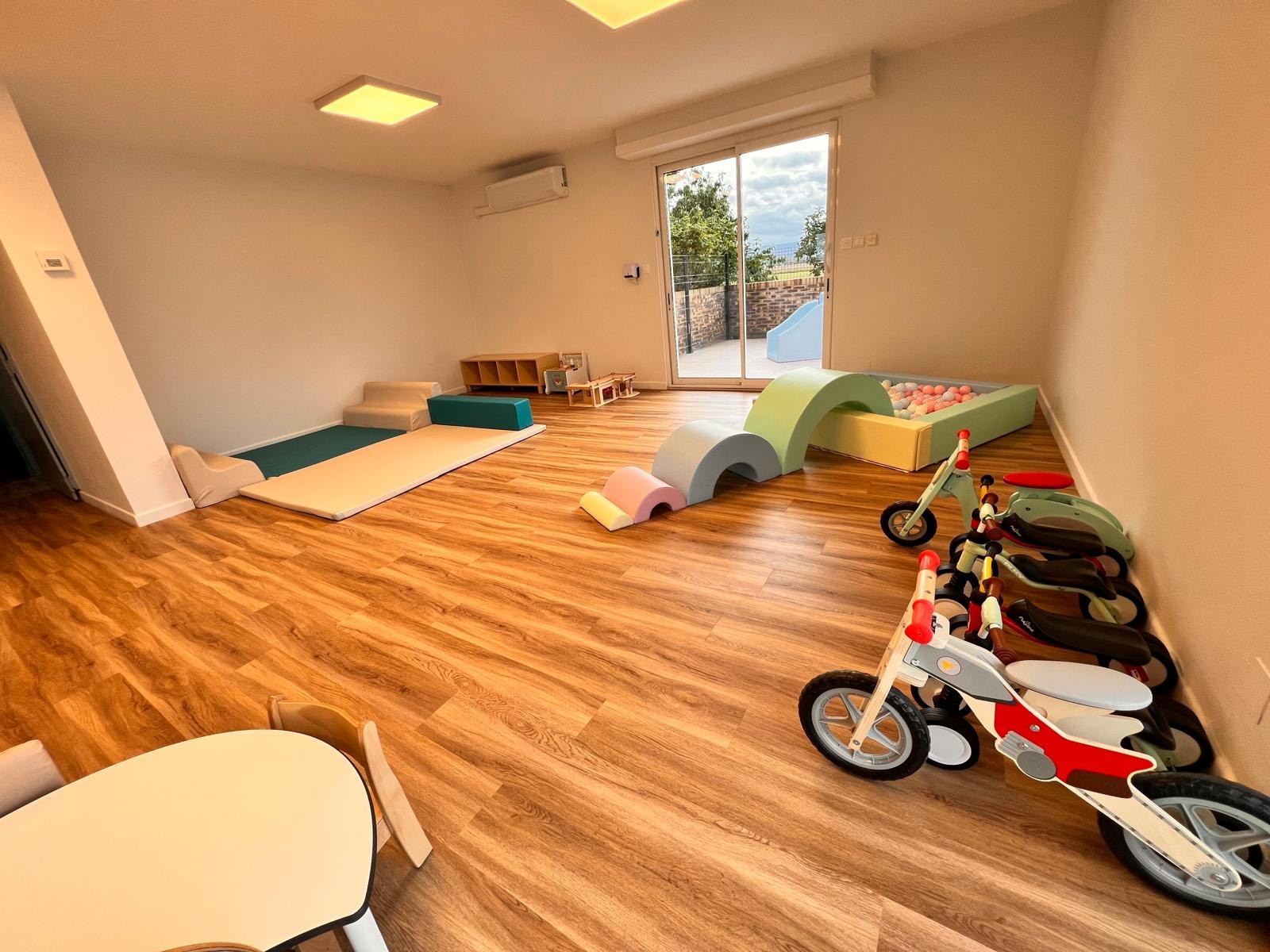 Espace de motricité libre de la micro-crèche Mélisse à Dachstein : modules en mousse, piscine à balles, tapis et porteurs en bois