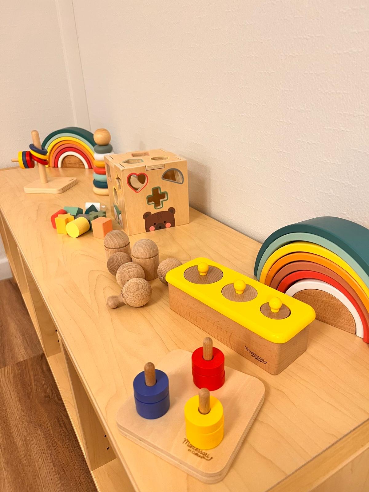 Jeux d’éveil Montessori en bois de la micro-crèche Mélisse à Dachstein : arc-en-ciel, cube à formes, tours d’empilage et encastrements