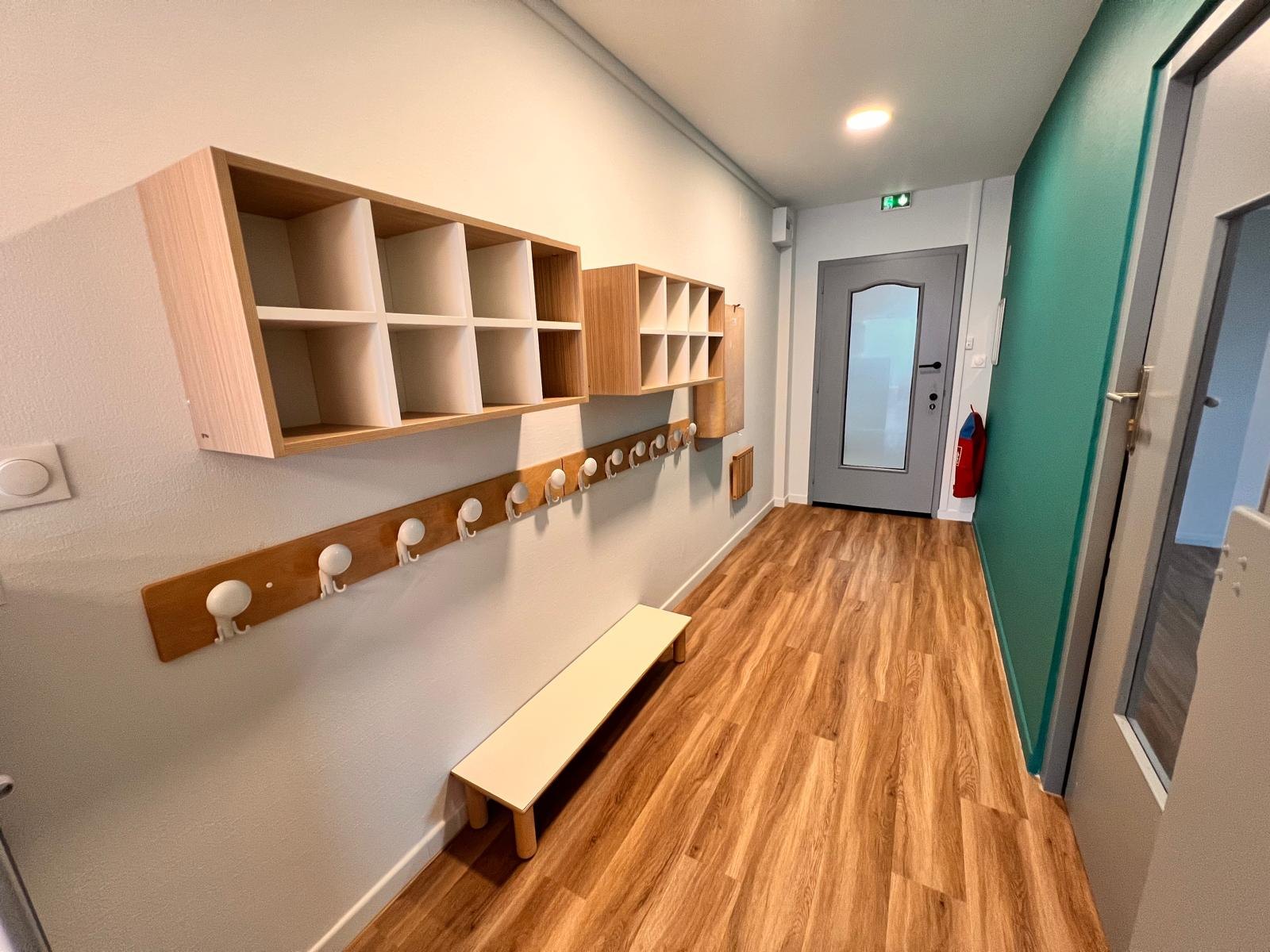 Vestiaire de la micro-crèche Mélisse à Dachstein, avec casiers individuels en bois, patères à hauteur d’enfant et banc bas